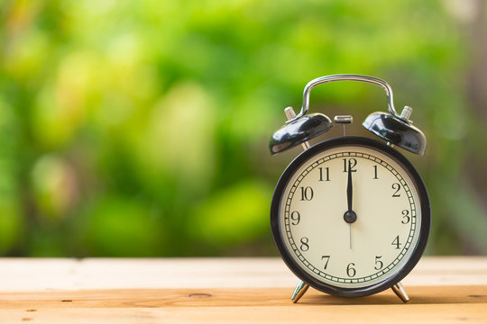 clock on wood table in the green garden time at 12 o'clock