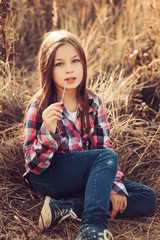 Obraz premium adorable kid girl in plaid shirt on sunny summer field, cozy mood, soft warm toned