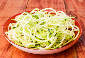 plate of raw zucchini spaghetti on wooden