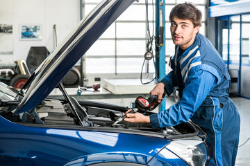 Male Mechanic Filling Oil Into Car's Engine At Garage