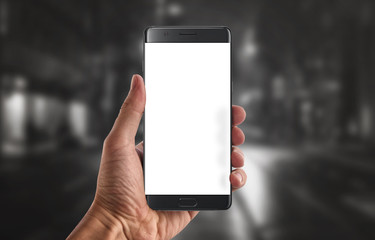 Modern black smart phone with isolated white display for mockup in man hand. Black background.