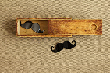 Hipster background. Fancy mustache in an old box. Vintage style.