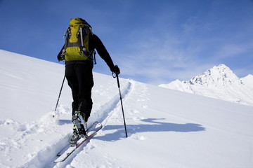 personne qui marche dans la neige au sommet des montagnes avec des peaux de phoque