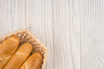 Buns in a wicker basket on old wooden table.