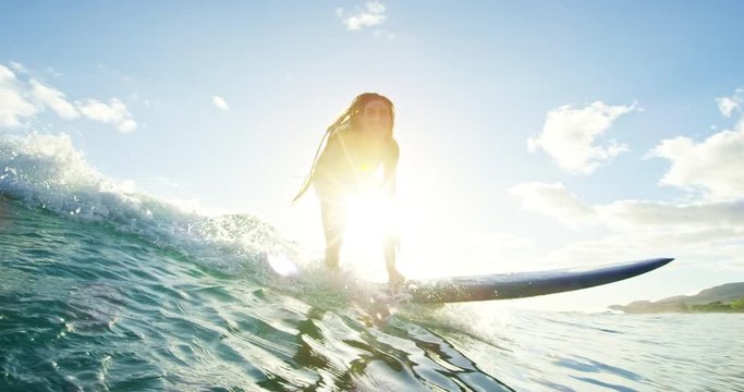 Beautiful surfer girl riding wave at sunset