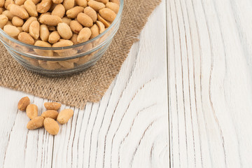 Salted peanuts in a glass bowl on the old wooden table.