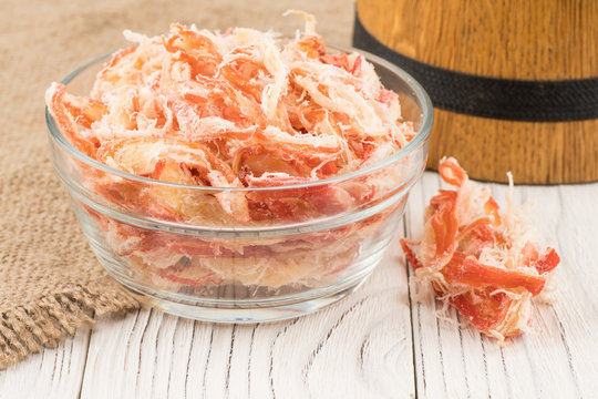 Dried squid in a glass bowl on old wooden table.