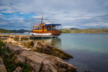 Isolated boat stopped and anchored in the calm waters and colorful, Kornati islands, Dalmatia,...