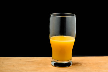 Glass of orange juice on wooden desk.