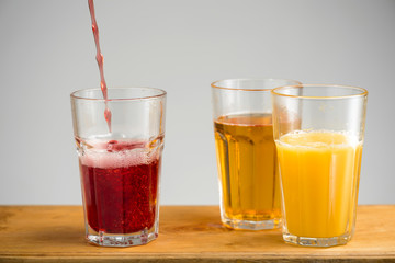 Glasses with apple, orange and cherry juice.