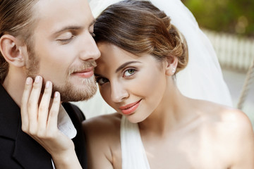 Happy beautiful newlyweds in suit and wedding dress smiling, enjoying.