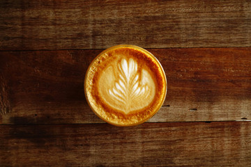 cup of latte art coffee on wooden background