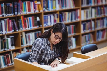 Female student writing notes in library