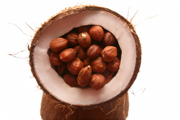 hazelnuts in a split coconut on white background