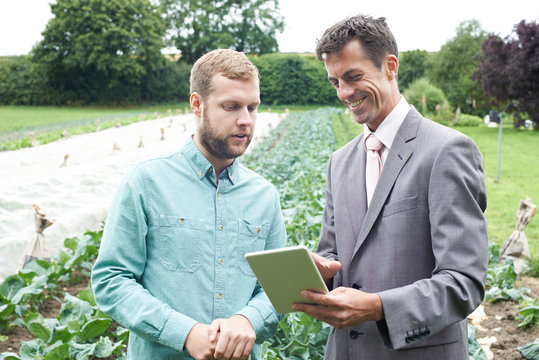 Businessman Using Digital Tablet During Meeting With Farmer In F