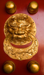Fototapeta na wymiar Golden ornament on a red wooden door in the Forbidden City, Beijing, China