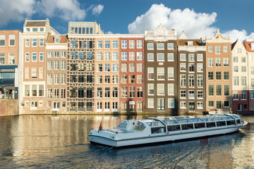 Naklejka premium Amsterdam canal cruise ship with Netherlands traditional house 