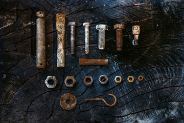 Set of rusty screws, nuts and small tools on a dark wooden backg