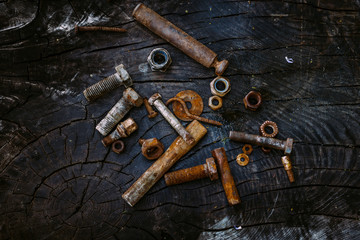 Fototapeta na wymiar Set of rusty screws, nuts and small tools on a dark wooden backg