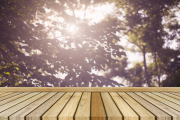 Empty top wooden table and blurred nature leave and sunrays in background. Can use for product display