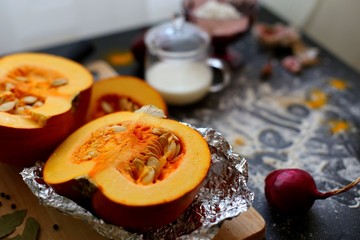 Fresh pumpkin slice on a black wooden table with flour texture. Autumn cooking background. Healthy eating. Top view.