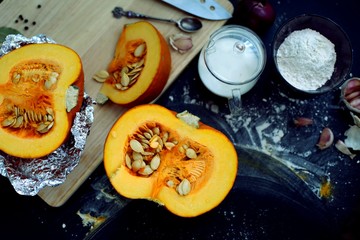 Fresh pumpkin slice on a black wooden table with flour texture. Autumn cooking background. Healthy eating. Top view.