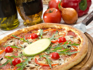 pizza with cherry tomatoes and salami, decorated with rucola on wooden board, ready to eat