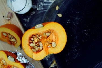 Fresh pumpkin slice on a black wooden table with flour texture. Autumn cooking background. Healthy eating. Top view.
