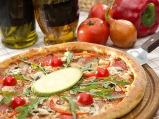 italian pizza on wooden board with tomatoes, onion, pepper and olive oil on background