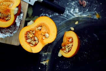 Fresh pumpkin slice on a black wooden table with flour texture. Autumn cooking background. Healthy eating. Top view.