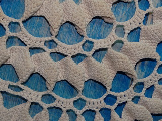 красивая старая вязаная салфетка лежит на синих деревянных досках   