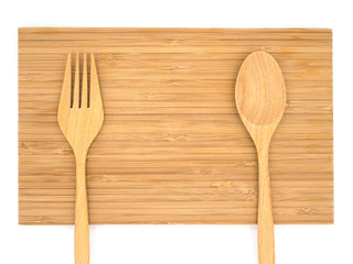 Top view of a wooden cutting board with wooden spoon and fork wi