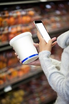 Woman using mobile phone while shopping for grocery