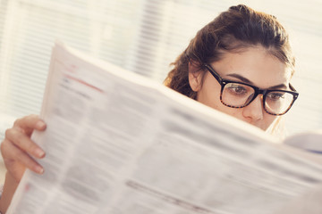 Young woman reading newspaper