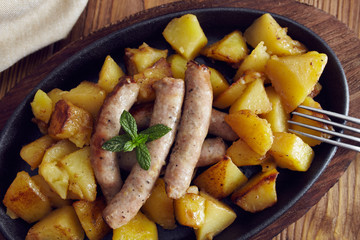 roasted sausages and potatoes on a wooden table