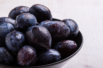 fresh plums in black bowl