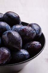fresh plums in black bowl