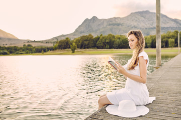 woman sitting at a dock reading a book