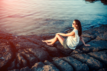 Pretty brunette girl relaxing in the stones