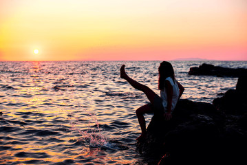 girl sitting on the stone at sunset time