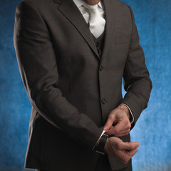 Business man adjusting his sleeve, on a blue background, stock picture