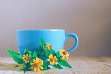 flowers and light blue cup on wooden table, vintage style