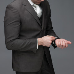 Business man adjusting his sleeve, on a grey background, stock picture