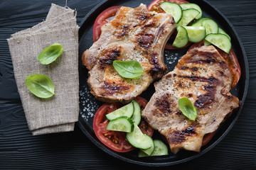 Frying pan with bbq pork chop steaks and vegetables, top view