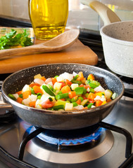 Vegetables cooking in frying pan on gas stove