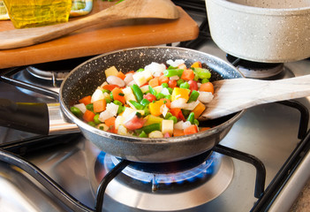 Vegetables cooking in frying pan on gas stove