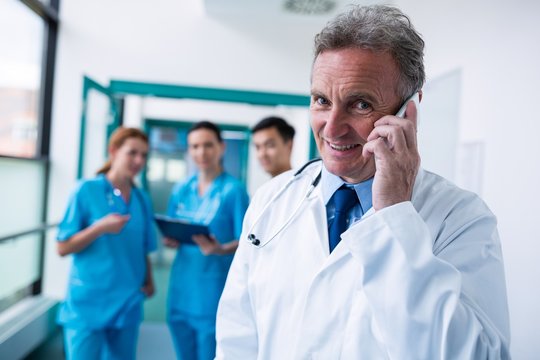 Portrait of smiling doctor talking on mobile phone in corridor