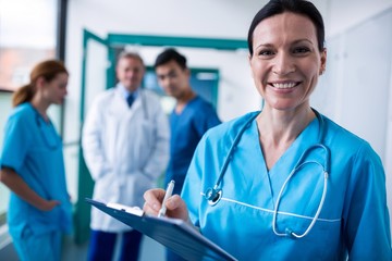 Portrait of smiling surgeon writing on clipboard