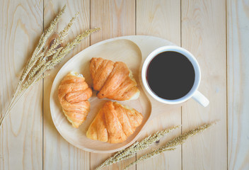 croissants with cup of coffee on wooden background
