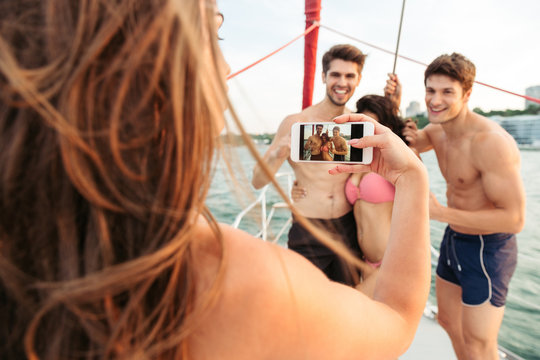 Girl making picture of her friends having fun on yacht